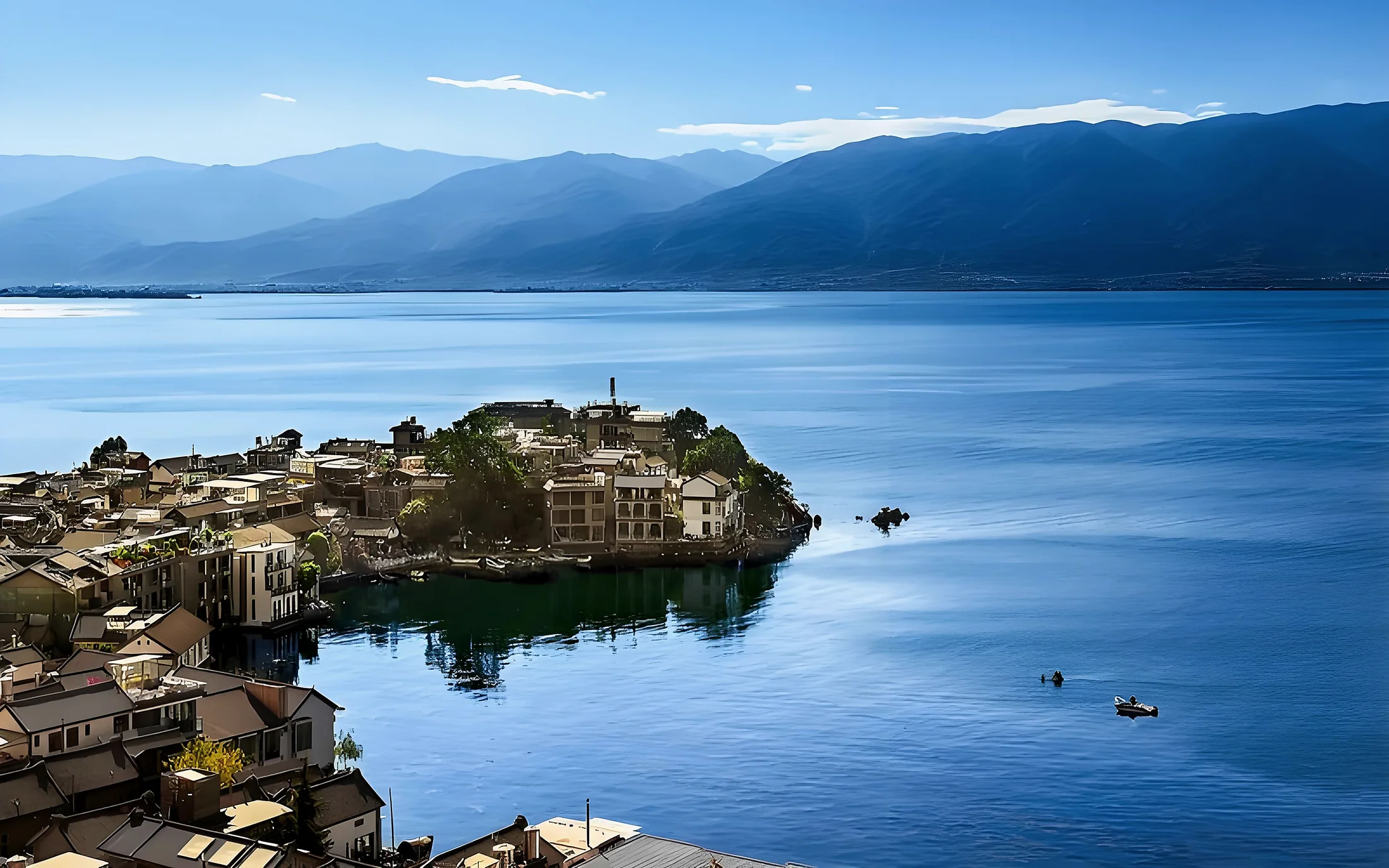 A village peninsula extending into Erhai Lake beneath mountains near Dali