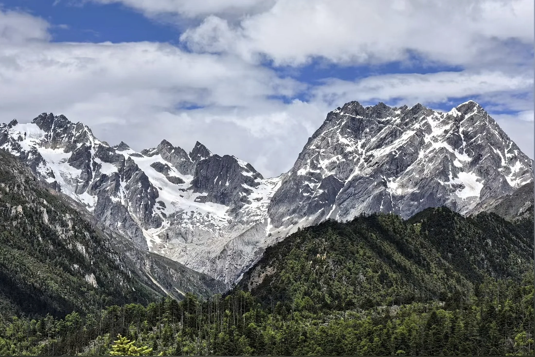 Snow-covered ridges of Jade Dragon Snow Mountain above forest near Lijiang